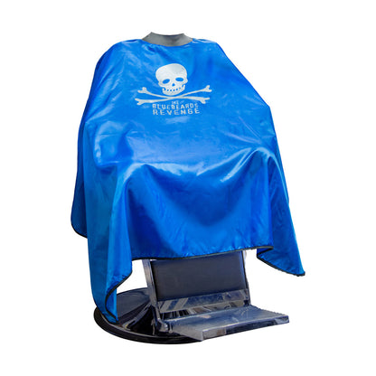 The Bluebeard's Revenge Neocape Barber Gown displayed on a barber chair, featuring a bold blue design with a skull and crossbones logo for style and protection.