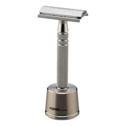 Feather All Stainless Safety Razor placed on its stainless steel stand with a close-up view of the engraved logo.