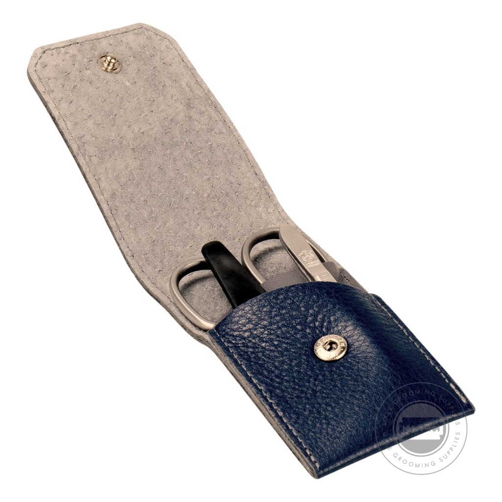 The open Dovo navy blue leather manicure set, revealing three stainless steel tools – nail scissors, tweezers, and a nail file – neatly placed within a grey suede interior.