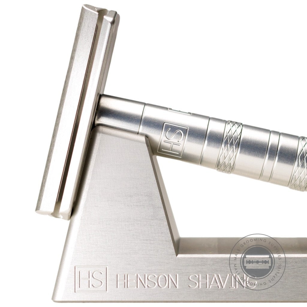 Close-up view of the Henson AL13 Safety Razor V2.0 in Aircraft Aluminium, highlighting the sleek and durable construction on its stand.