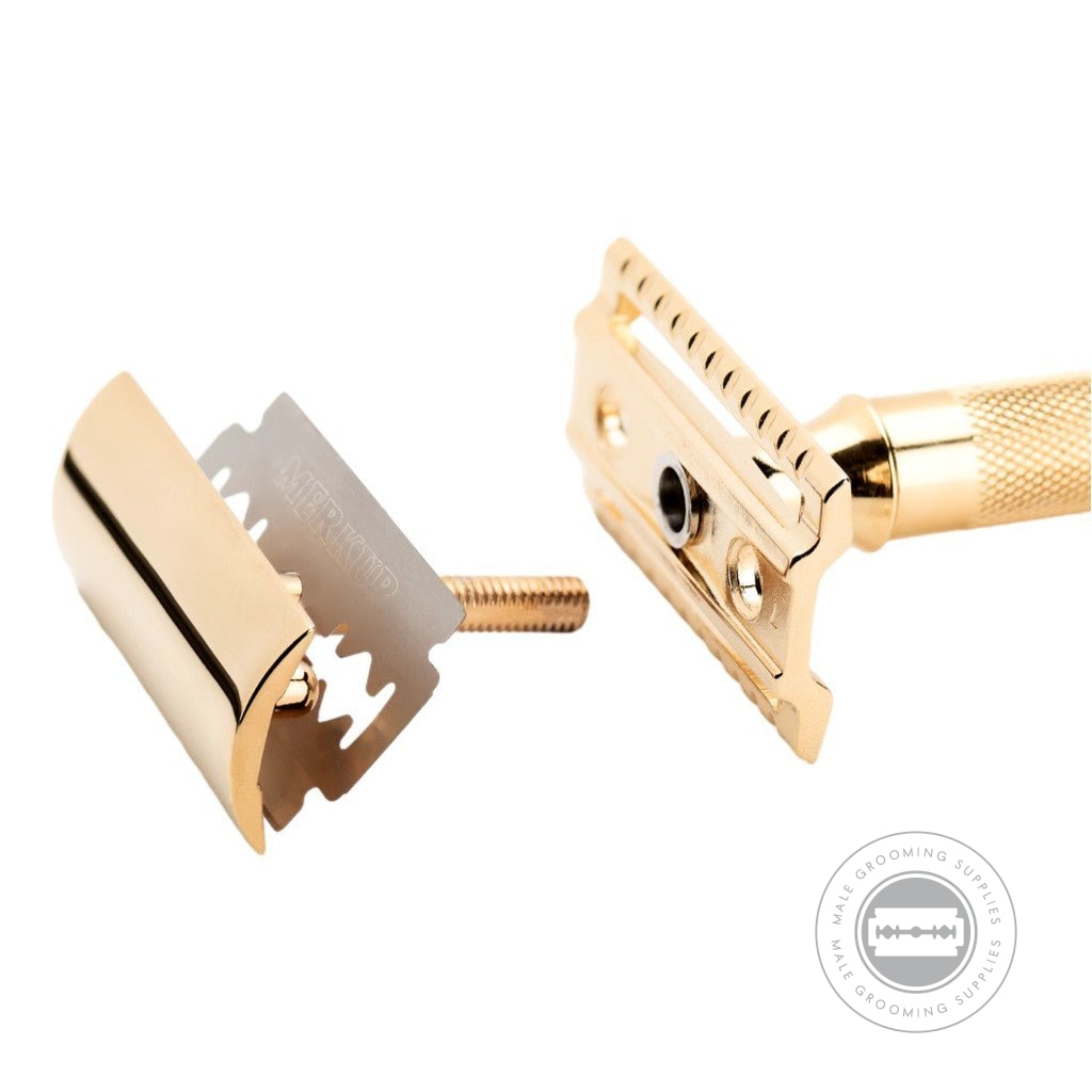 Disassembled Merkur 34003 Gold-Plated Safety Razor, showing the blade, top plate, and bottom plate with gold finish.